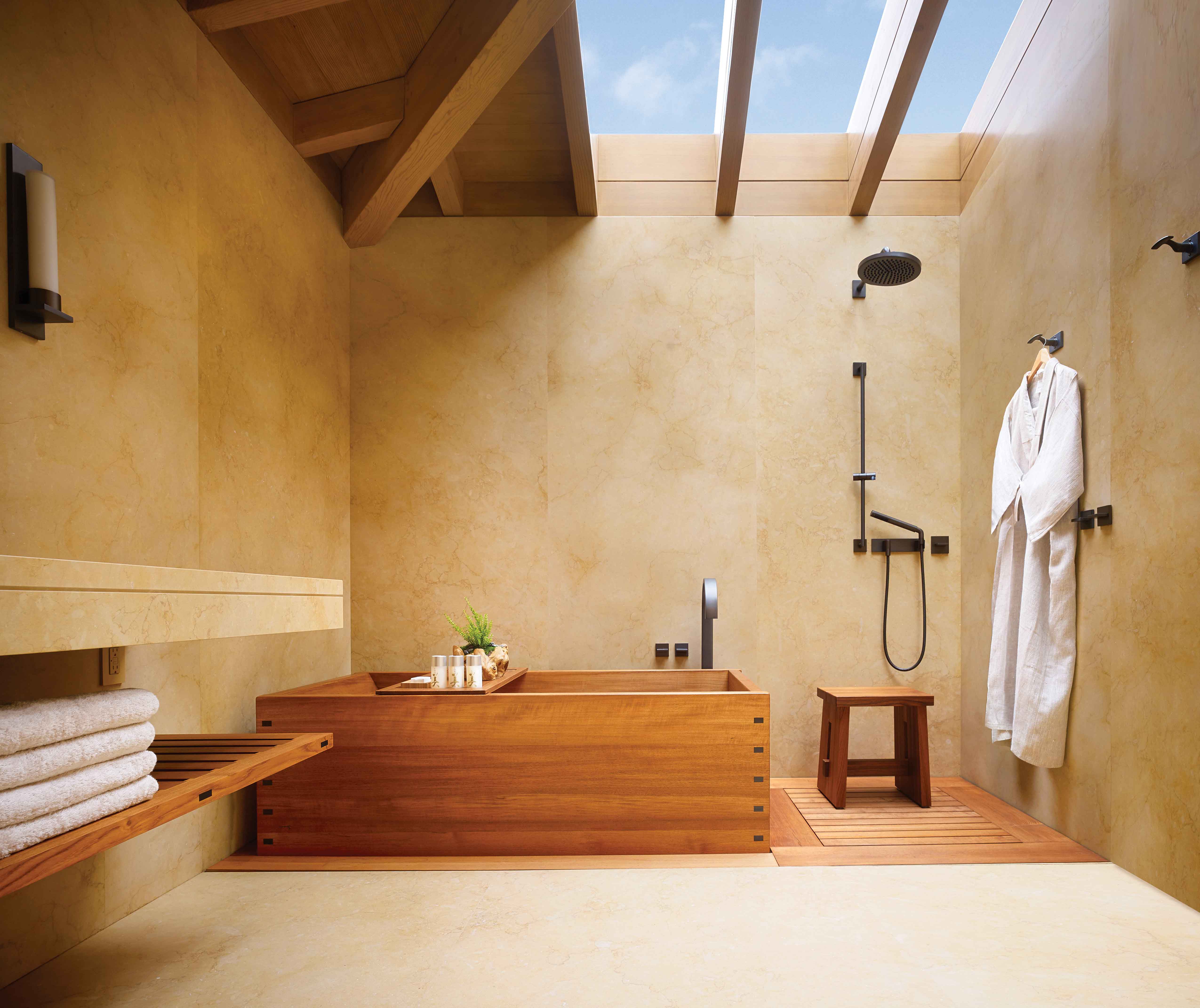 The bathroom of one of the bedrooms with a rainfall shower, teakwood soaking tub, Nobu robe hung on the wall, exposed ceilings and wooden interiors